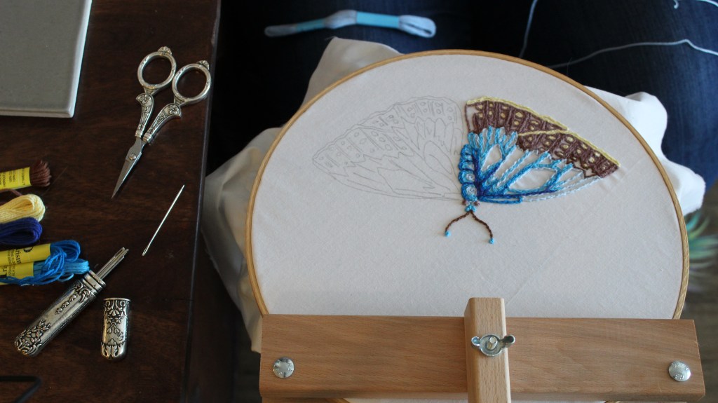 Film still of blue butterfly embroidery instruction video from the #stitchtogether series Amanda Beasley put together for the McClung Museum.